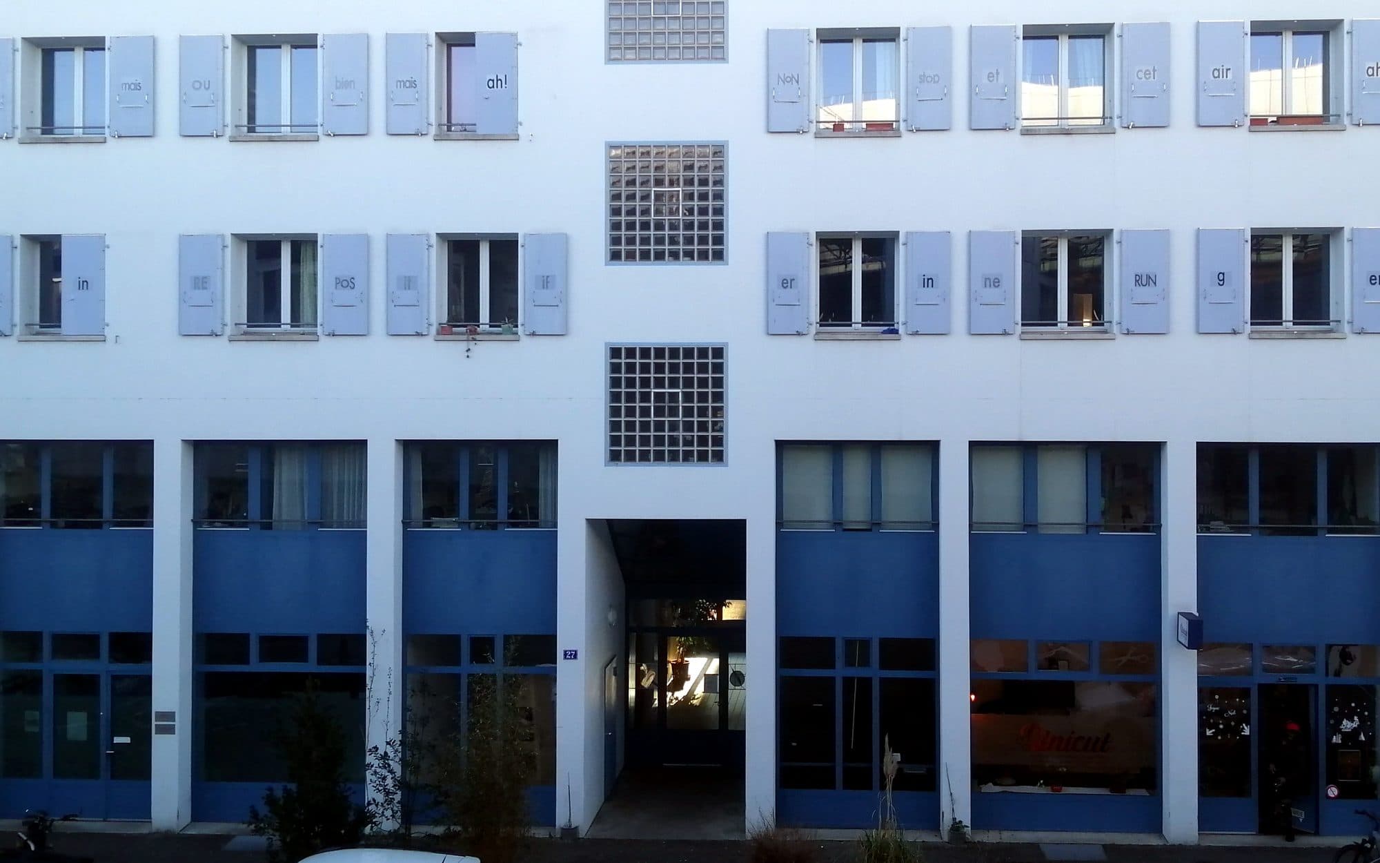 La façade blanche et bleue du 27 rue des Gares, dont les volets portent une œuvre typographique